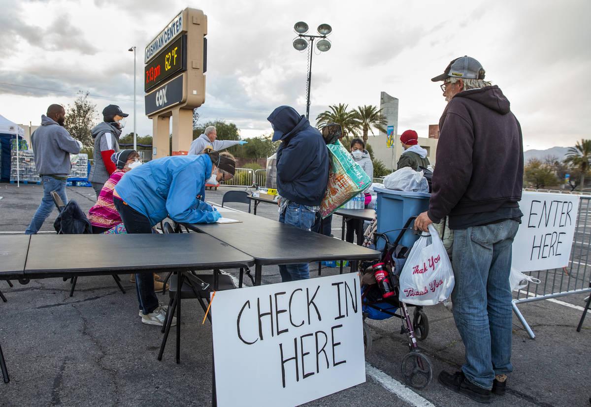 Homeless people enter and receive sheets and water at the temporary shelter in the upper parkin ...