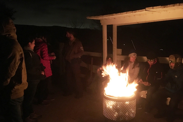 Hikers gather around a fire before departing on a 2-mile trek. BRIAN SANDFORD/VIEW