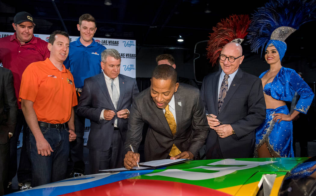 Clark County Commissioner and Las Vegas Convention and Visitors Authority Board Chairman Lawrence Weekly, center, signs the contract as the LVCVA joined with Las Vegas Motor Speedway officials to  ...