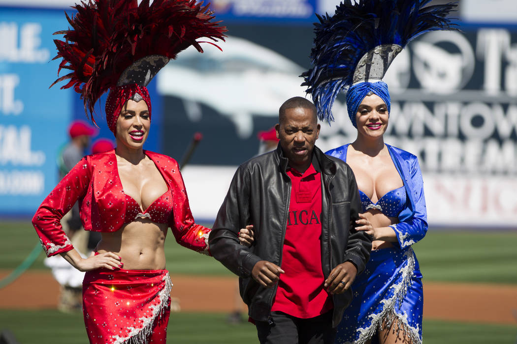 Clark County Commissioner Lawrence Weekly, center, walks off the field with two Las Vegas showgirls during a Big League Weekend baseball game at Cashman Field on Saturday, March 25. (Erik Verduzco ...