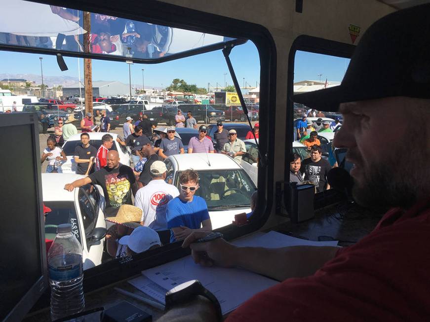 TNT Auction owner and chief auctioneer Mike McKee drives up the bid price on a vehicle. (Brian ...