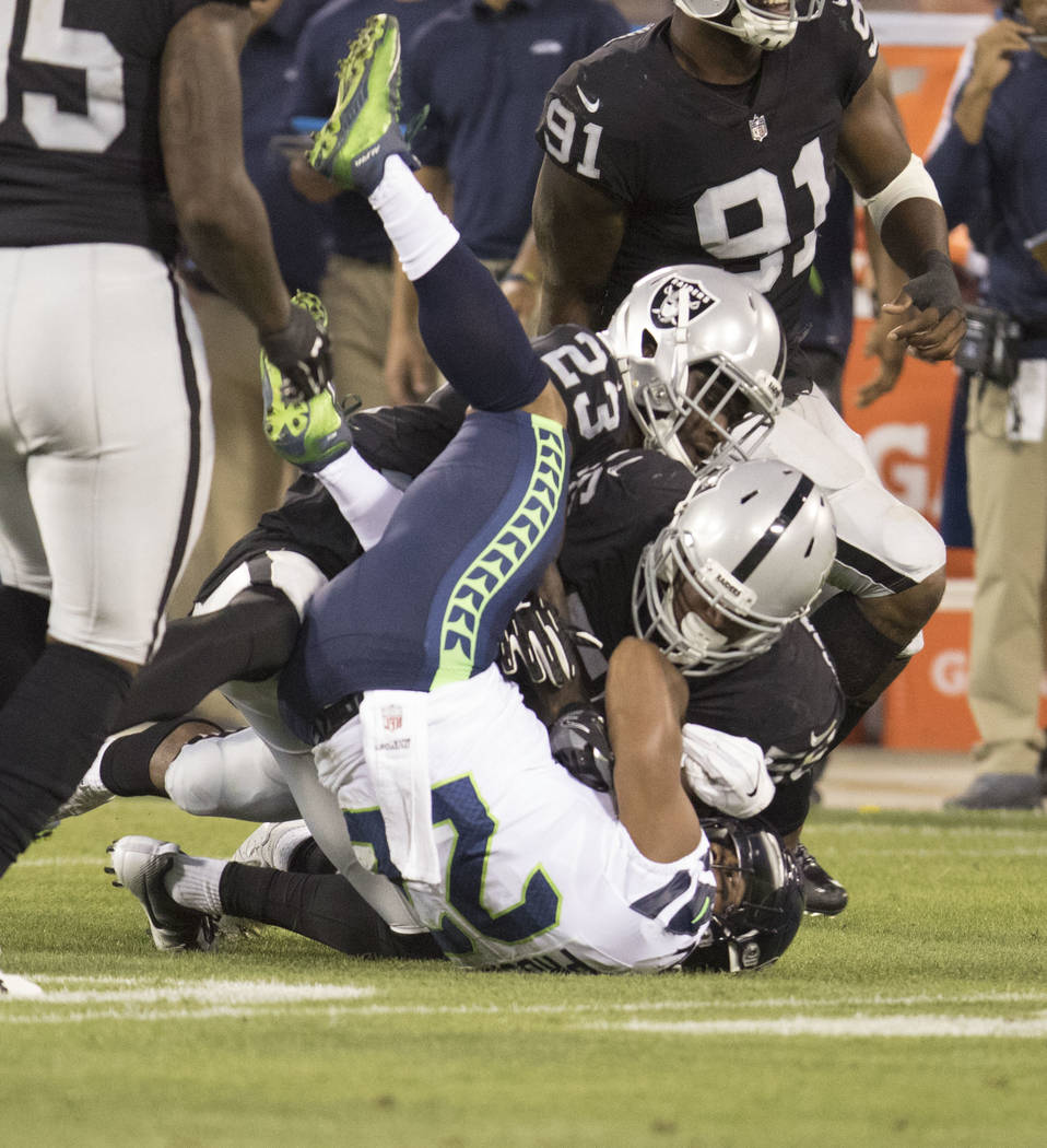 Oakland Raiders linebacker Xavier Woodson-Luster (56) tackles ball carrier Seattle Seahawks running back C.J. Prosise (22) in the first half of the preseason game in Oakland, Calif., Thursday, Aug ...