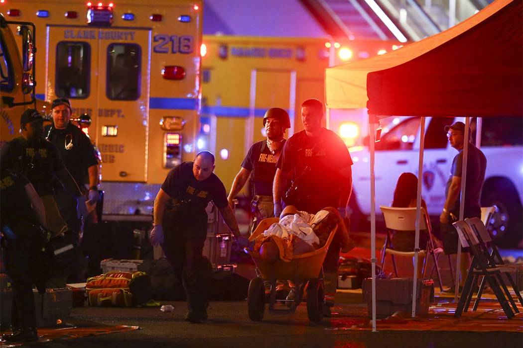 A wounded person is walked on a wheelbarrow as Las Vegas police respond during an active shooter situation on the Las Vegas Strip in Las Vegas on Sunday, Oct. 1, 2017. (Chase Stevens/Las Vegas Rev ...