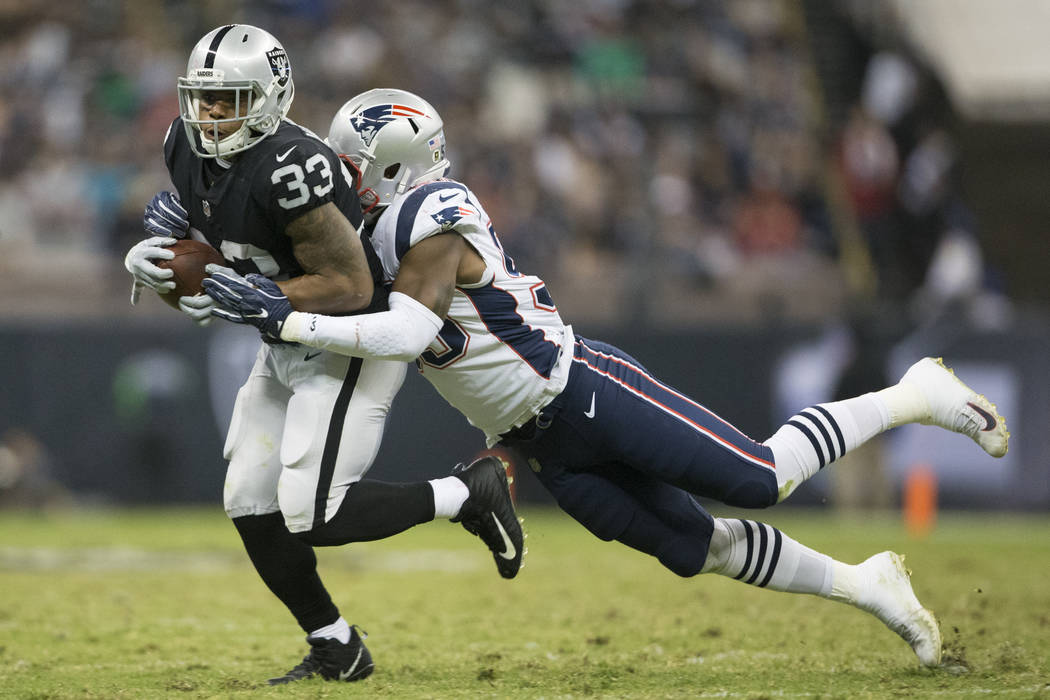 Oakland Raiders running back DeAndre Washington (33) is tackled by New England Patriots linebacker Marquis Flowers (59) after a catch in the NFL football game at Estadio Azteca in Mexico City, Sun ...