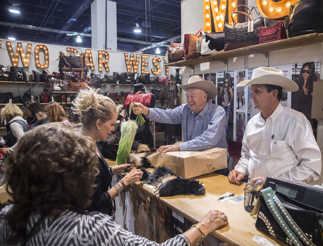 Danny McFadin, middle, hands Kathleen Newton, left, her new clothing during Cowboy Christmas on ...