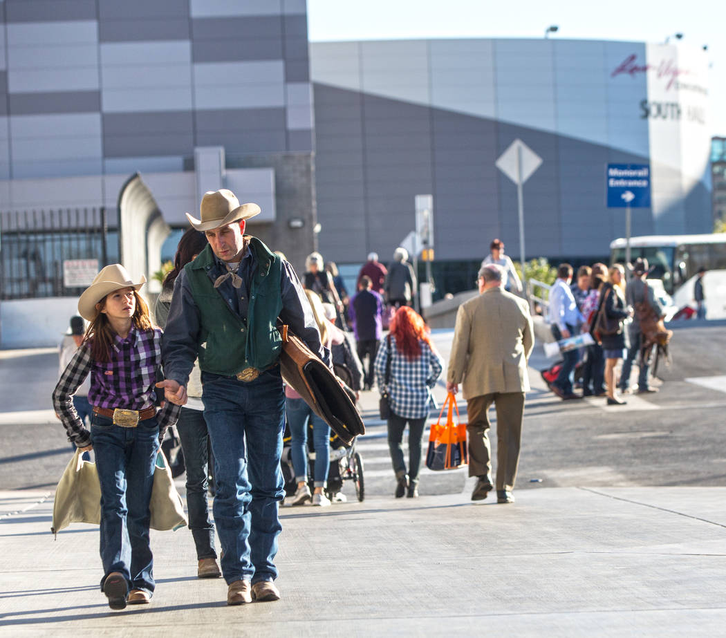 Attendees of Cowboy Christmas walk out of the Las Vegas Convention Center with bags in hand on ...
