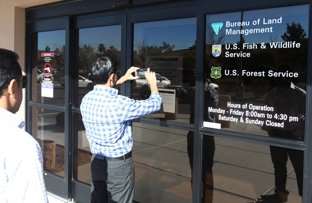 Umer Malik takes a photo of a closed sign at a U.S. Government office building at 4701 N. Torrey Pines Drive in Las Vegas Monday, Jan. 22, 2018. Malik and his brother Imran Malik, left, were at th ...