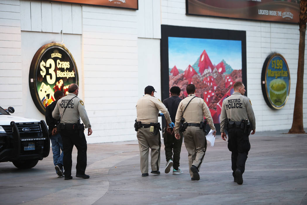 Metro officers walk away with handcuffed individuals near the Fremont Street Experience in Las Vegas, Monday, Jan. 15, 2018. A large fight occurred nearby with around 100 people involved and eight ...