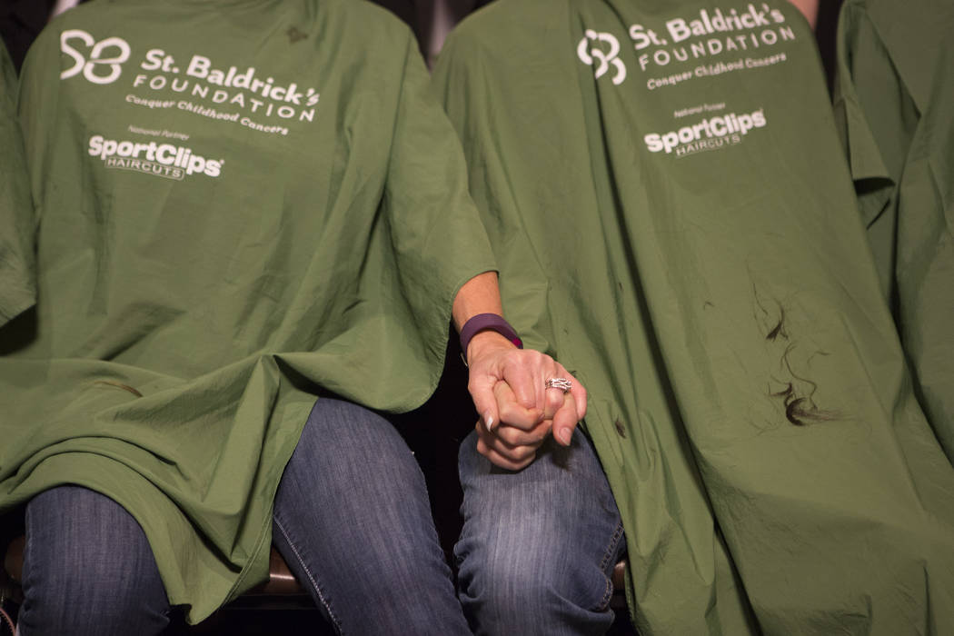 Kathy Haynie, left, holds Shaun Haynie's, her step-son, hand while they get their heads shaved part of "Shave for the Cure" a St. Baldrick's event held at McMullan's Irish Pub on Saturda ...