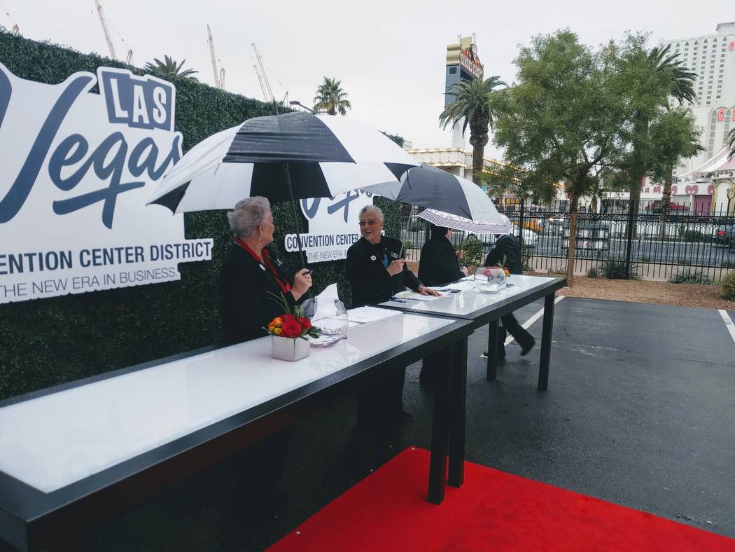 Staff greeting attendees of the groundbreaking marking the expansion of the Las Vegas Convention Center break out umbrellas Monday, Jan. 8, 2018, as rain fell in Las Vegas, Nev. The expanded conve ...
