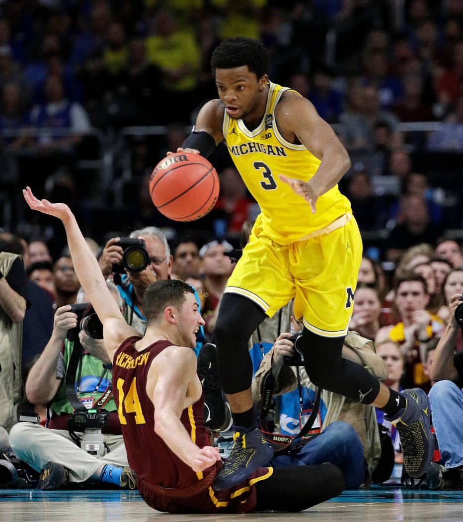 Michigan's Zavier Simpson (3) drives the ball against Loyola-Chicago's Ben Richardson (14) during the second half in the semifinals of the Final Four NCAA college basketball tournament, Saturday,  ...