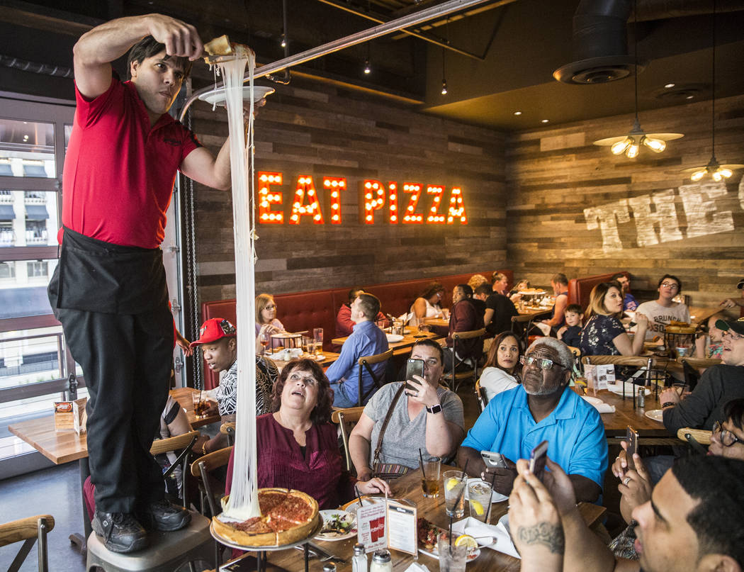 Server Gonzalo Acera, left, stretches mozzarella cheese nearly 10 feet high while serving an extra cheese deep dish pizza at Giordano's on Sunday, March 26, 2017, in Las Vegas. (Benjamin Hager/Las ...