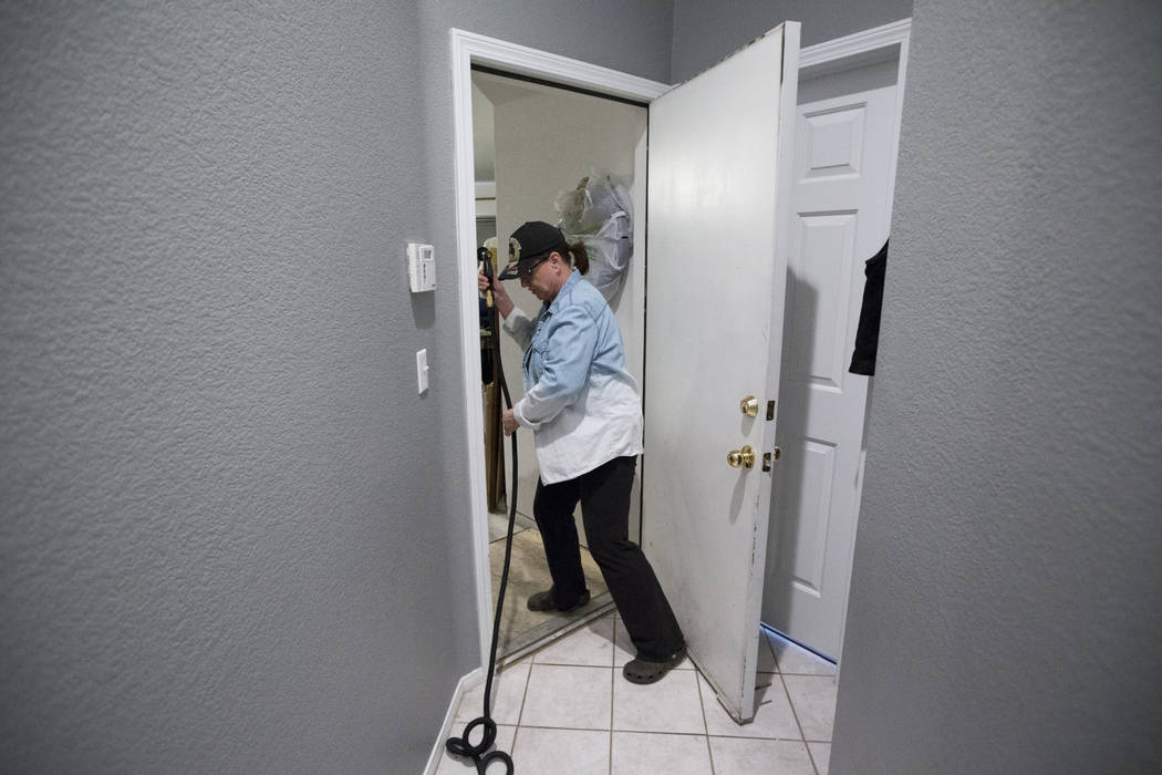 Dana Wagner, wife of military veteran Ed Wiesing, not pictured, shows how she uses a hose from a bathroom to the garage to shower her husband who recently became paralyzed from his legs, at their ...