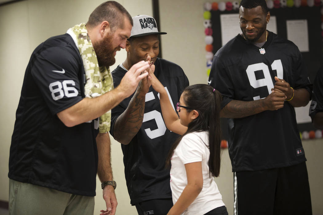 Oakland Raiders players Lee Smith, from left, Bruce Irvin, and Shilique Calhoun congratulate Guadalupe Galicia Hernandez, 9, who won a raiders themed drawing contest at Gene Ward elementary school ...