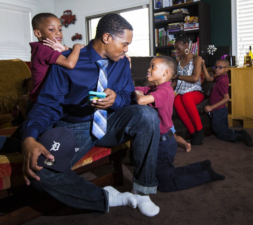 Deon Derrico sits with his children, Deniko, 4, left, and Denver, 6, at their home in North Las ...