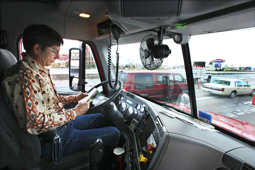 Tractor-trailer truck driver Gary Mott catches up on his reading on Interstate 15 in Primm on D ...