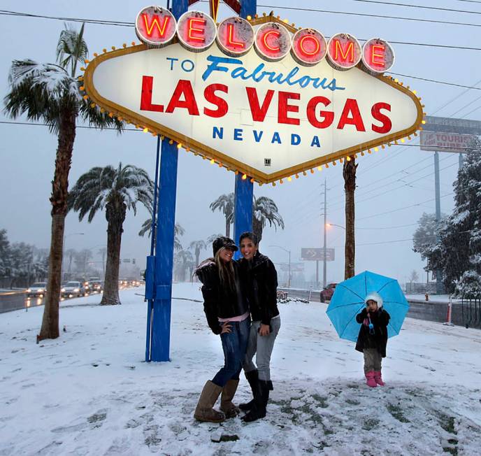 Visitors have their picture taken at the welcome sign during a snowstorm on the Las Vegas Strip ...