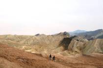 Hikers head across the badlands below Zabriskie Point in Death Valley National Park, California ...