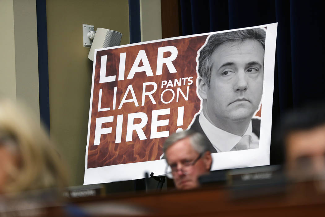 A poster on display during a hearing with Michael Cohen, President Donald Trump's former personal lawyer, before the House Oversight and Reform Committee on Capitol Hill in Washington, Wednesday, ...