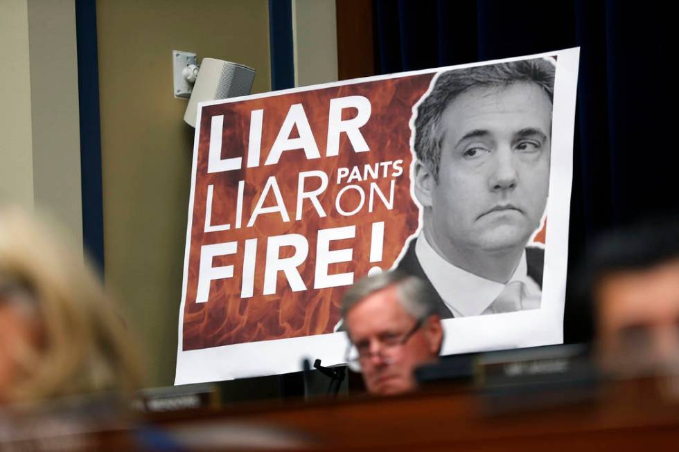 A poster on display during a hearing with Michael Cohen, President Donald Trump's former personal lawyer, before the House Oversight and Reform Committee on Capitol Hill in Washington, Wednesday, ...