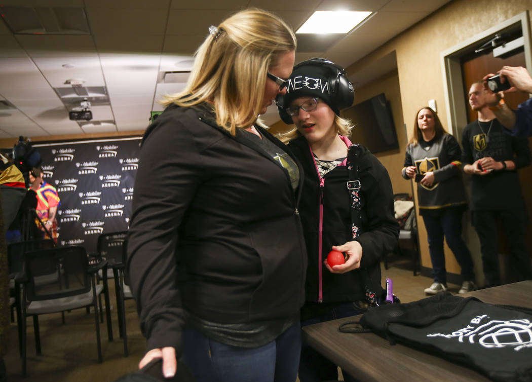 Jeanette Allison, left, talks with her daughter Kristlynn Allison, 11, as she wears noise-cancelling headphones and plays with a fidget toy from a sensory bag before a Golden Knights game at T-Mob ...