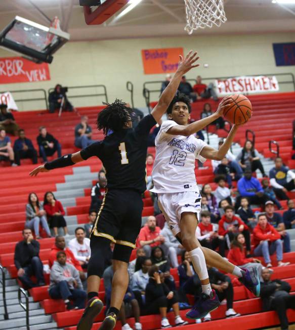 Desert Pines' Milos Uzan (12) goes to the basket against Clark's Frankie Collins (1) during the first half of a Class 4A state boys basketball quarterfinal game at Arbor View High School in Las Ve ...