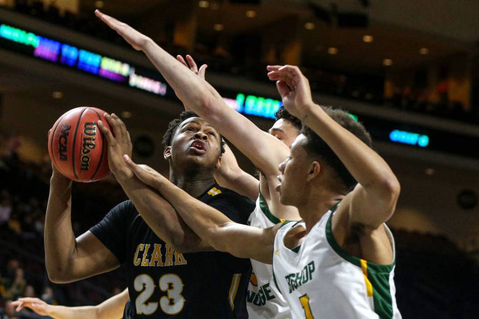 Clark's Antwon Jackson (23) looks to take a shot while being guarded by Bishop Manogue's Joshua Rolling (1) and Daniel Bansuelo (3) during the first half of a Class 4A state boys basketball semif ...