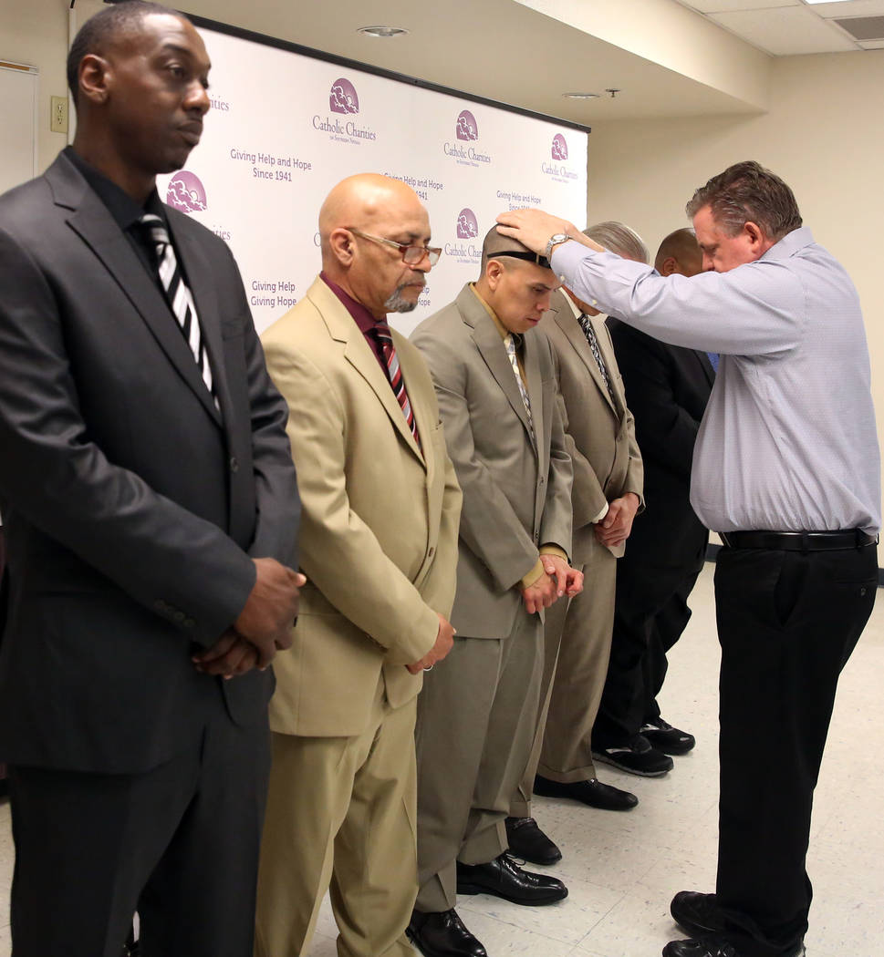 Deacon Thomas Roberts, president and chief executive officer of Catholic Charities, blesses graduates Broderick Gray, left, Theodore Hines, Derrick Johnson, center, Ricky Delucia, and John Bontemp ...