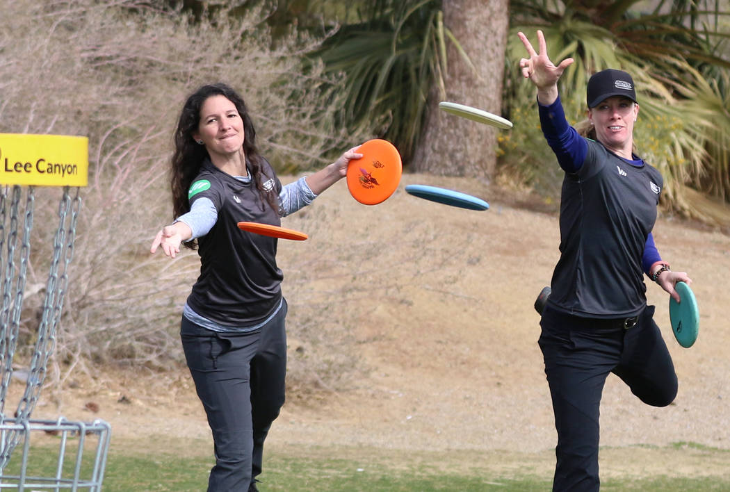 Madison Walker of Pensacola, Fla., left, and Ellen Widboom of Brooksville , Fla., attempt to throw their discs into the basket during practice at Wildhorse Golf Club on Wednesday, Nov. 20, 2019, ...