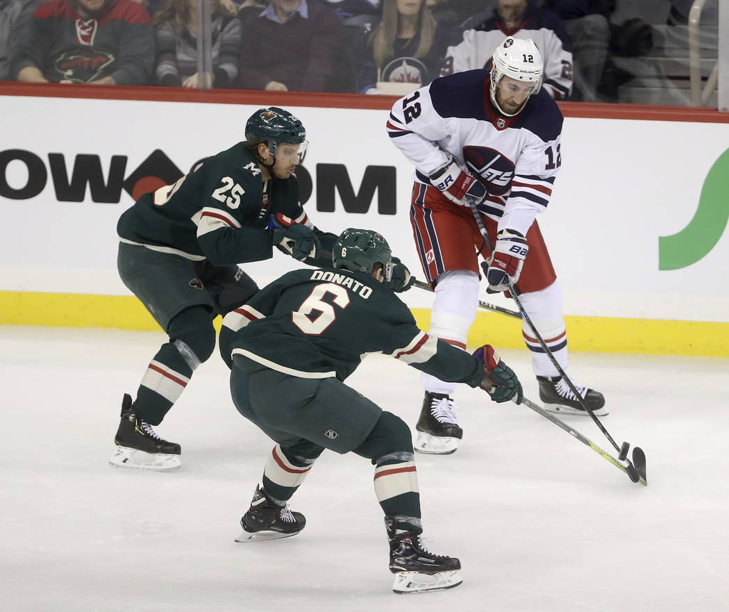 Winnipeg Jets' Kevin Hayes (12) plays the puck in front of Minnesota Wild Jonas Brodin (25) and Ryan Donato (6) during the first period of an NHL hockey game Tuesday, Feb. 26, 2019, in Winnipeg, M ...