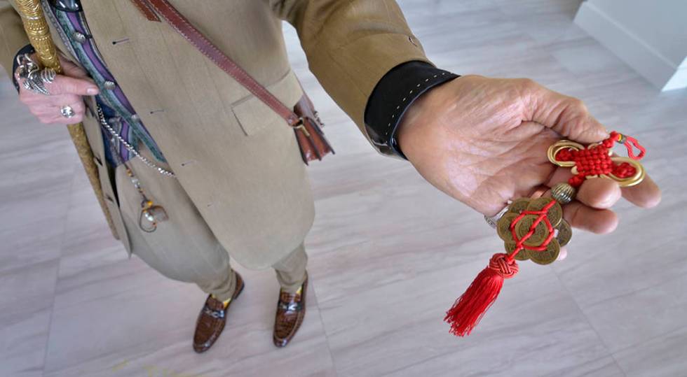 Doc Phineas Kastle holds Chinese money coins. The round coins with a square center represent the union between earth and heaven. The coins are tied together with a red ribbon and hung in the wealt ...