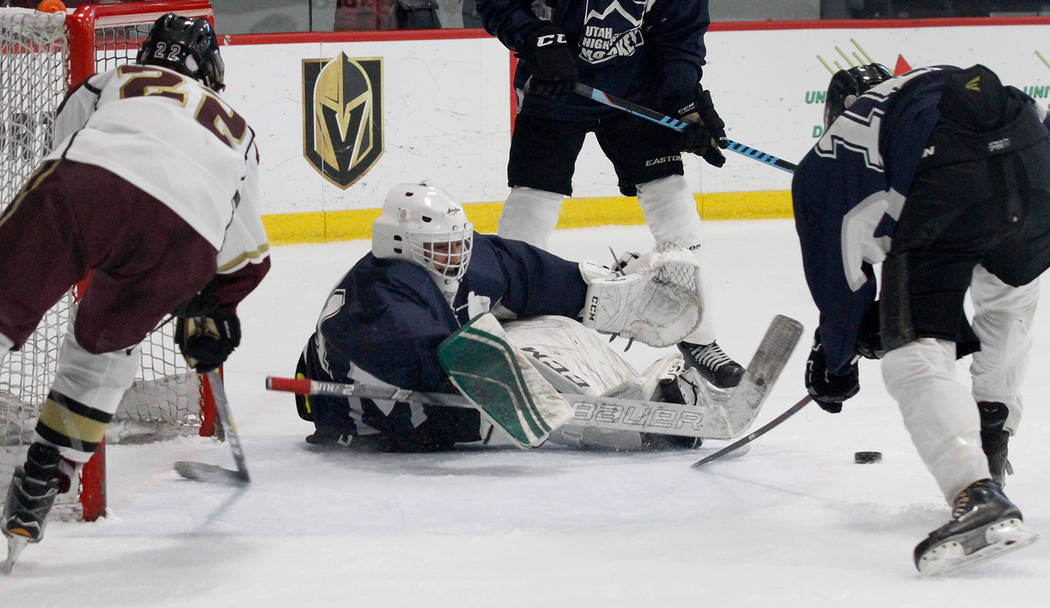 Utah's goaltender Landon Palmer, center, makes a save against Faith Lutheran's Hunter Keech (22) during the second period of a hockey game at the City National Arena in Las Vegas, Saturday, Dec. 1 ...