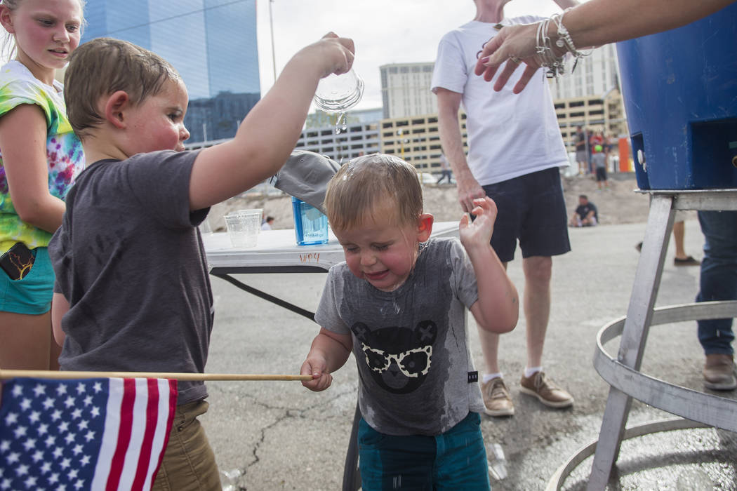 Sawyer Tuck, 4, pours water on his brother Oliver Tuck's head, 2, to cool down at the Evel Live event where Travis Pastrana attempted to exceed three of Evel Knievel's famous jumps in a lot behind ...