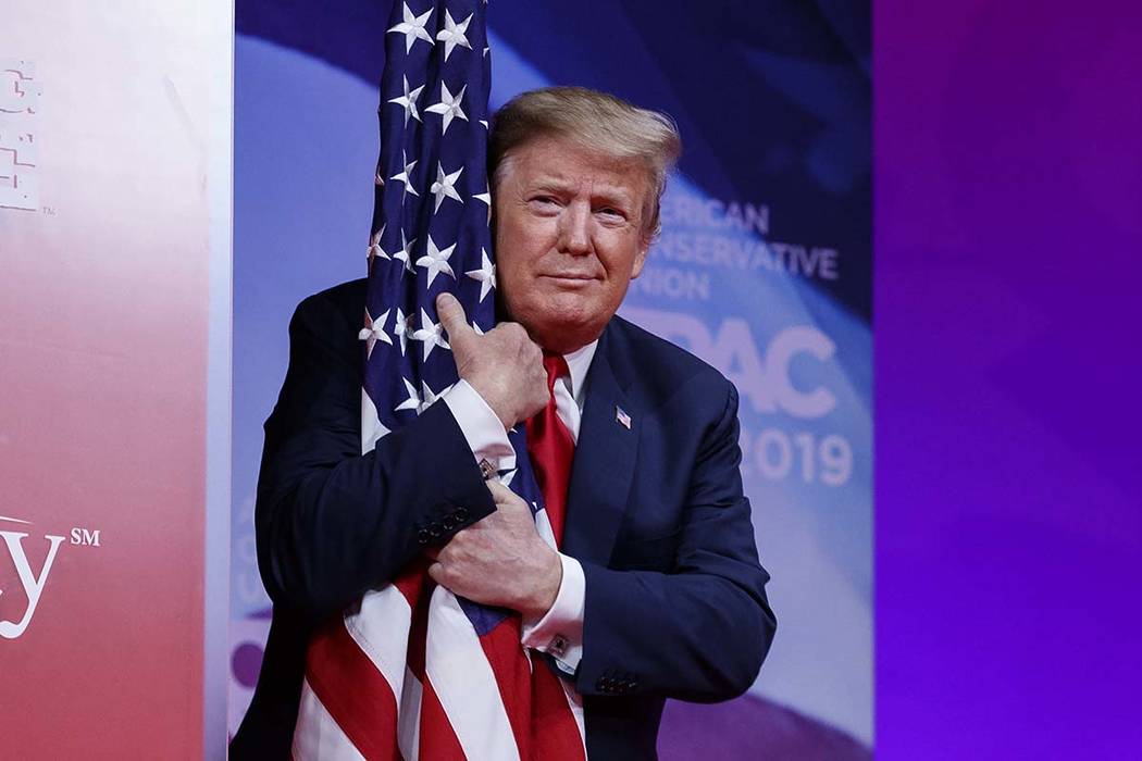 President Donald Trump hugs the American flag as he arrives to speak at Conservative Political Action Conference, CPAC 2019, in Oxon Hill, Md., Saturday, March 2, 2019. (AP Photo/Carolyn Kaster)