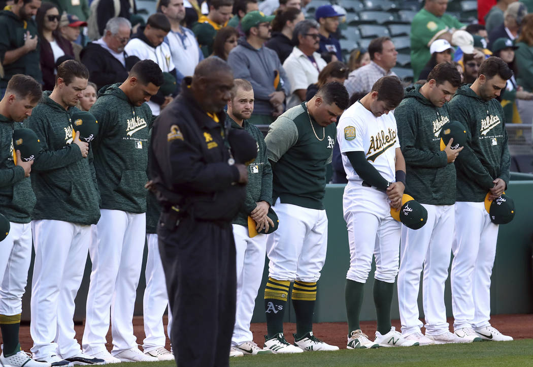 Oakland Athletics bow their heads in memory of Gretchen Piscotty, mother of right fielder Stephen Piscotty, prior to a baseball game against the Houston Astros Monday, May 7, 2018, in Oakland, Cal ...