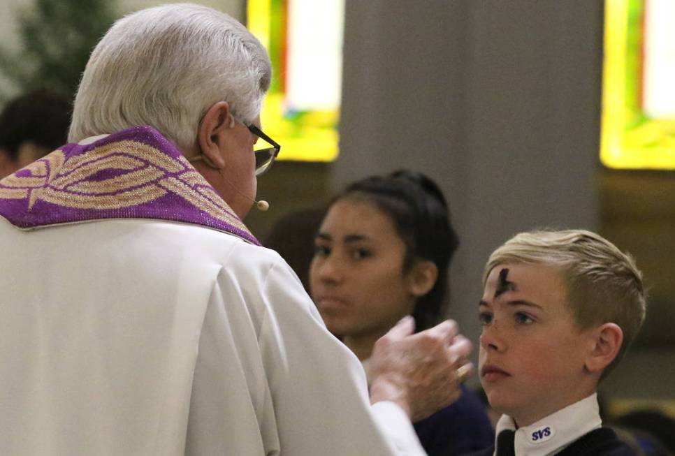 Rev. Larry Lentz applies ashes on St. Viator Parish School student Stryder Ratajczyk's forehead at St. Viator Catholic Church during Ash Wednesday on Wednesday, March. 6, 2019, in Las Vegas. Bizua ...