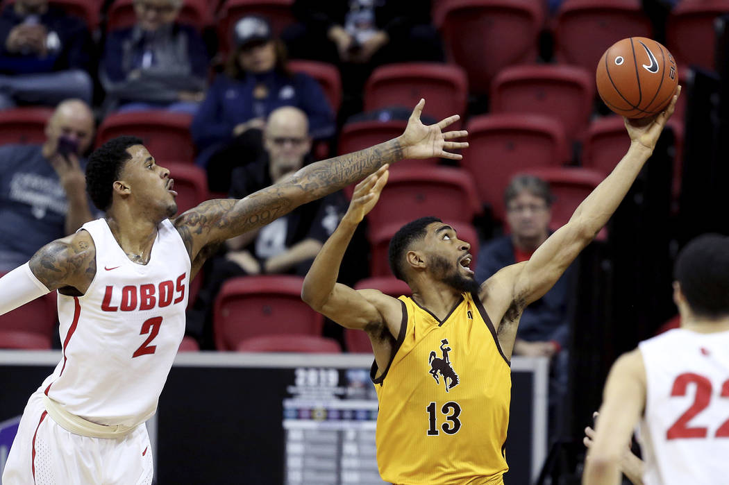 Wyoming's TJ Taylor (13) and New Mexico's Corey Henson (2) reach for a rebound during the first half of an NCAA college basketball game in the Mountain West Conference tournament, Wednesday, March ...