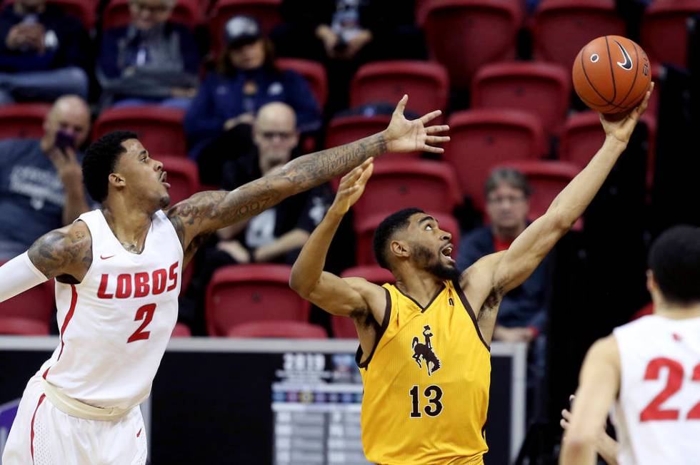 Wyoming's TJ Taylor (13) and New Mexico's Corey Henson (2) reach for a rebound during the first half of an NCAA college basketball game in the Mountain West Conference tournament, Wednesday, March ...