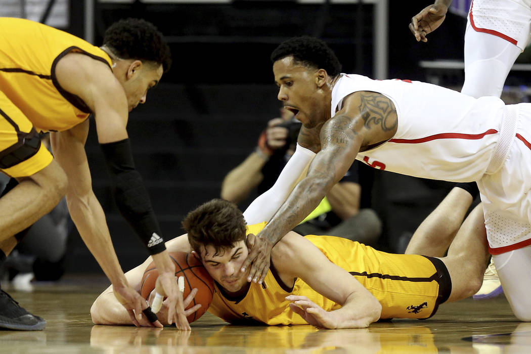 Wyoming's Hunter Thompson, center, Justin James, left, and New Mexico's Corey Henson reach for a loose ball during the first half of an NCAA college basketball game in the Mountain West Conference ...