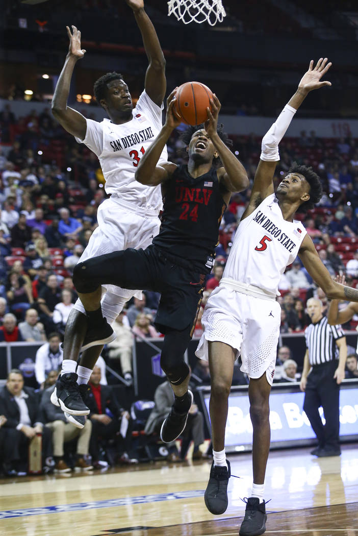 UNLV Rebels forward Joel Ntambwe (24) goes to the basket between San Diego State Aztecs forwards Nathan Mensah (31) and Jalen McDaniels (5) during the second half of a quarterfinal game in the Mou ...
