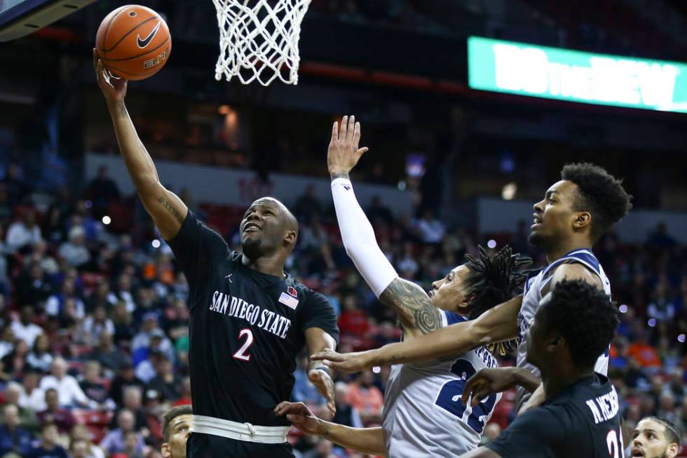 San Diego State Aztecs guard Adam Seiko (2) goes to the basket against UNR Wolf Pack guard Jazz Johnson (22) and forward Jordan Brown (21) during the first half of a semifinal basketball game in t ...