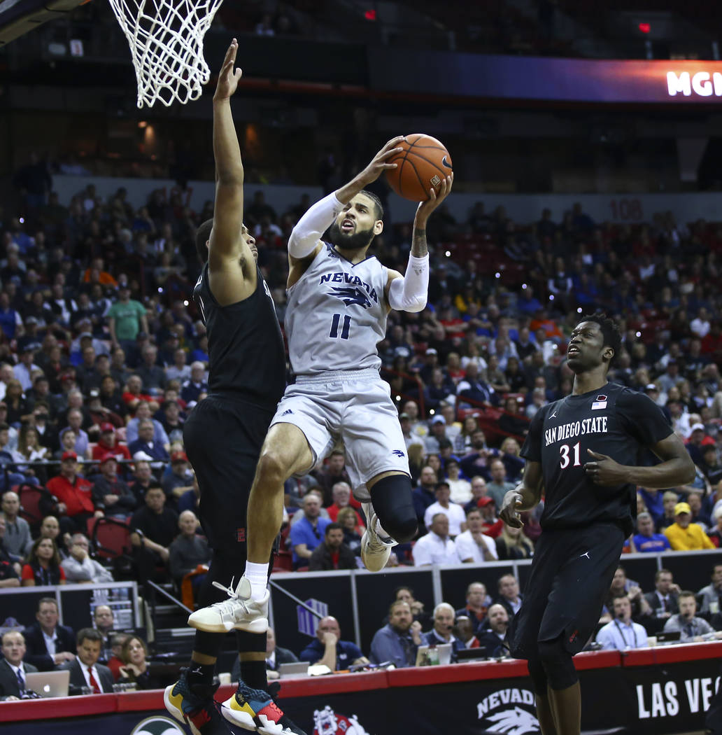 UNR Wolf Pack forward Cody Martin (11) goes to the basket between San Diego State Aztecs forwards Matt Mitchell and Nathan Mensah (31) looks on during the second half of a semifinal basketball gam ...