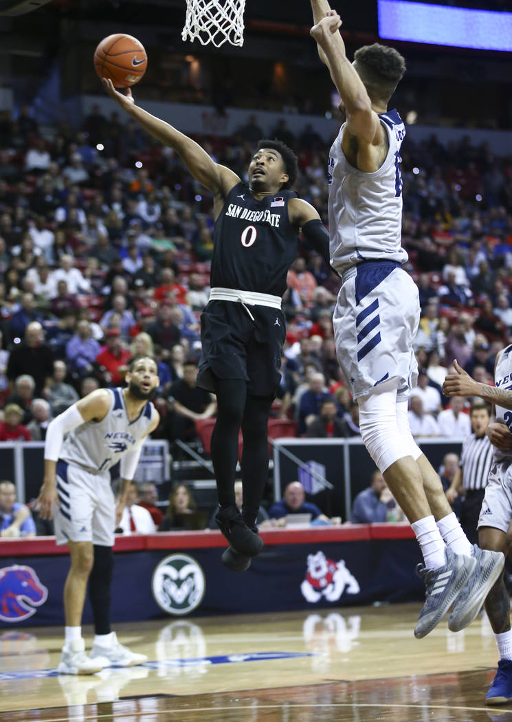 San Diego State Aztecs guard Devin Watson (0) goes to the basket against UNR Wolf Pack forward Trey Porter (15) during the first half of a semifinal basketball game in the Mountain West men's bask ...