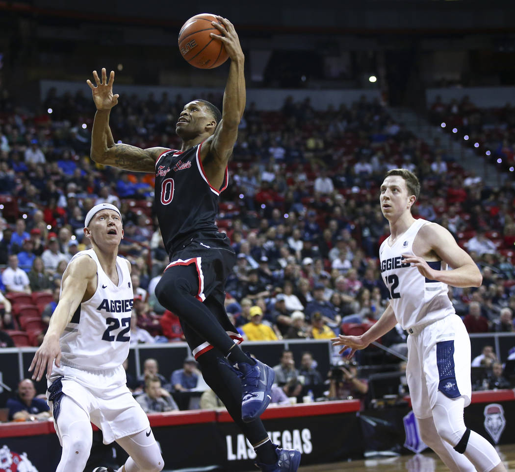 Fresno State Bulldogs guard New Williams (0) goes to the basket between Utah State Aggies guard Brock Miller (22) and forward Justin Bean (12) during the first half of a semifinal basketball game ...