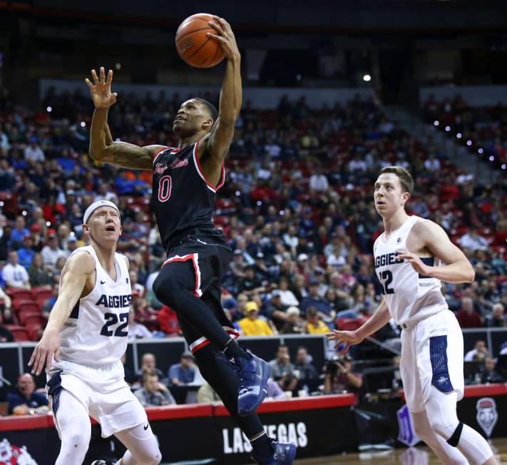 Fresno State Bulldogs guard New Williams (0) goes to the basket between Utah State Aggies guard Brock Miller (22) and forward Justin Bean (12) during the first half of a semifinal basketball game ...