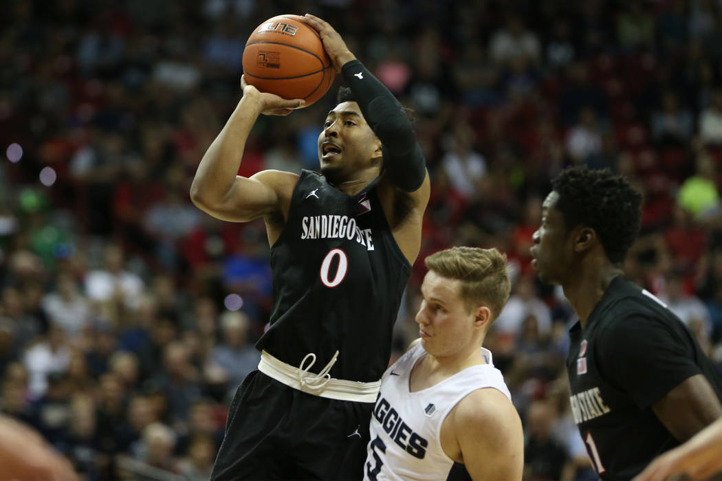 San Diego State Aztecs guard Devin Watson (0) shoots the ball for a score while getting fouled by Utah State Aggies guard Sam Merrill (5) for an extra point in the first half of the Mountain West ...