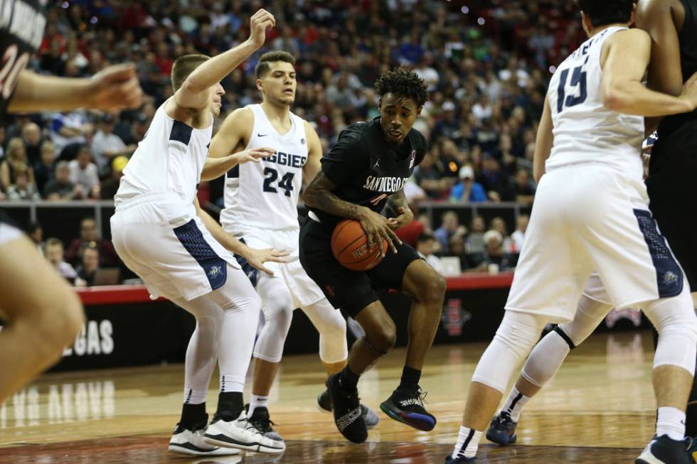 San Diego State Aztecs guard Jeremy Hemsley (42) drives the ball under pressure from Utah State Aggies forward Quinn Taylor (10) and guard Diogo Brito (24) in the first half of the Mountain West t ...