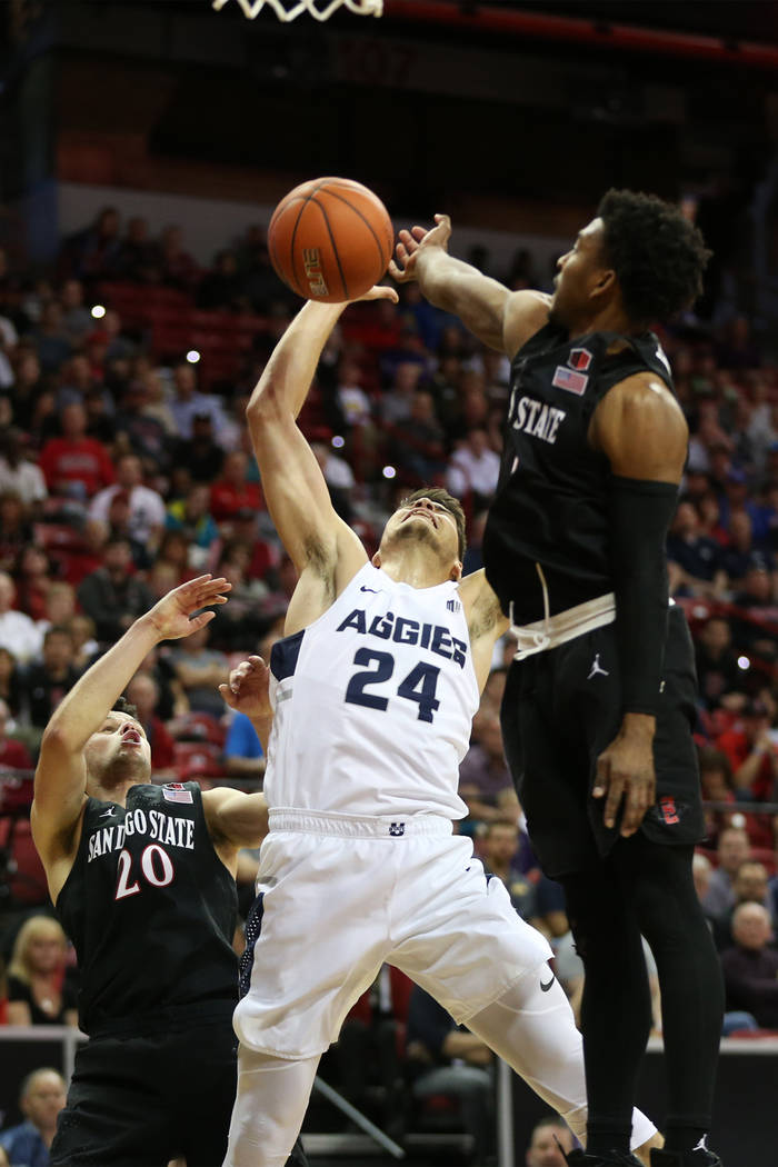 Utah State Aggies guard Diogo Brito (24) is fouled against San Diego State Aztecs guard Devin Watson (0) and guard Jordan Schakel (20) in the second half of the Mountain West tournament men's bask ...