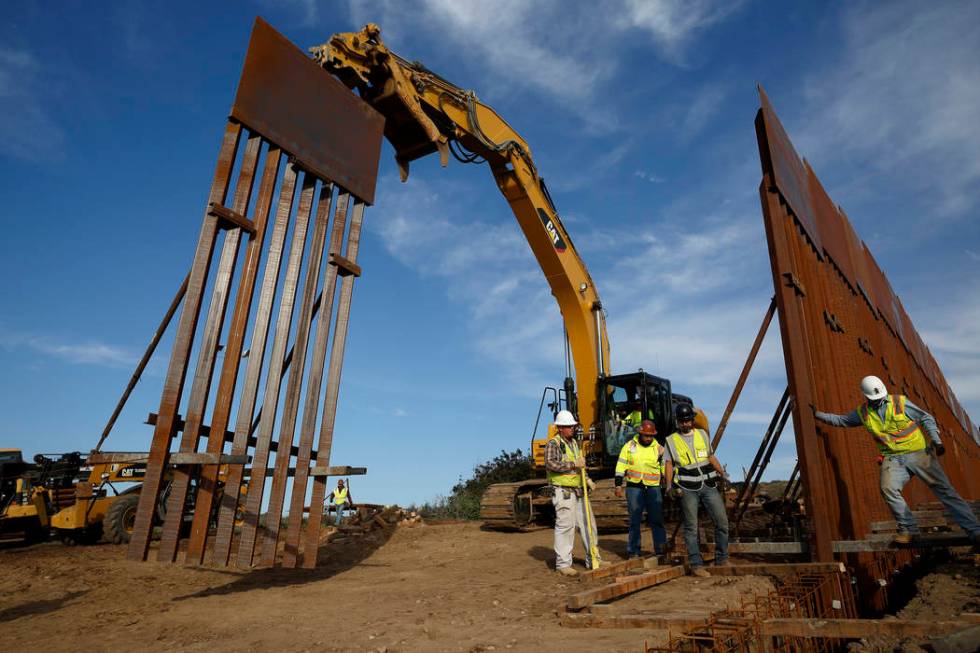 In this Jan. 9, 2019 file photo, construction crews install new border wall sections seen from Tijuana, Mexico. (AP Photo/Gregory Bull, File)