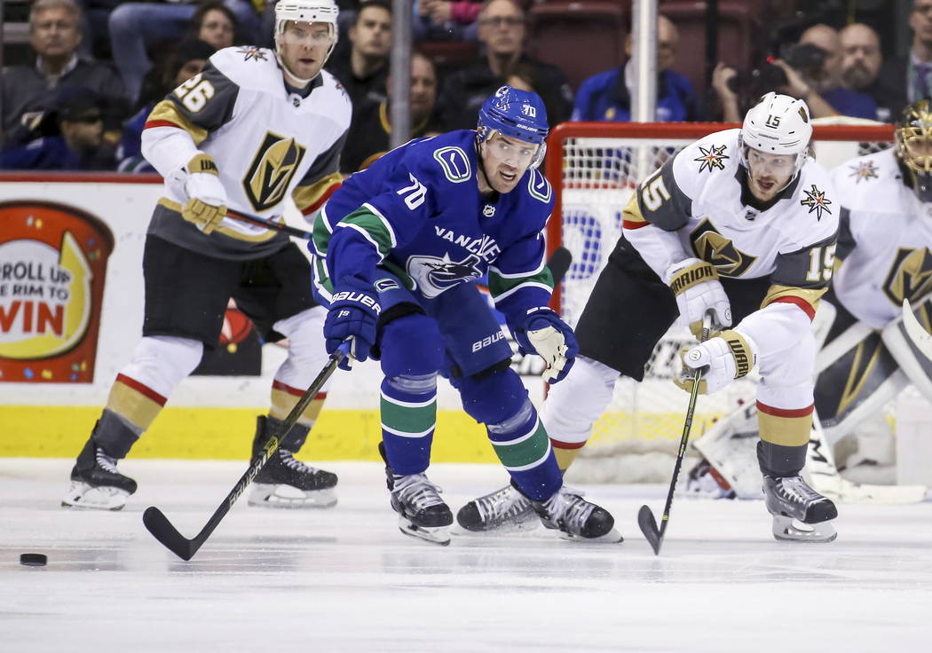 Vegas Golden Knights' Jon Merrill (15) fights for the puck against Vancouver Canucks' Tanner Pearson (70) during the second period of an NHL hockey game in Vancouver, British Columbia, Saturday, M ...